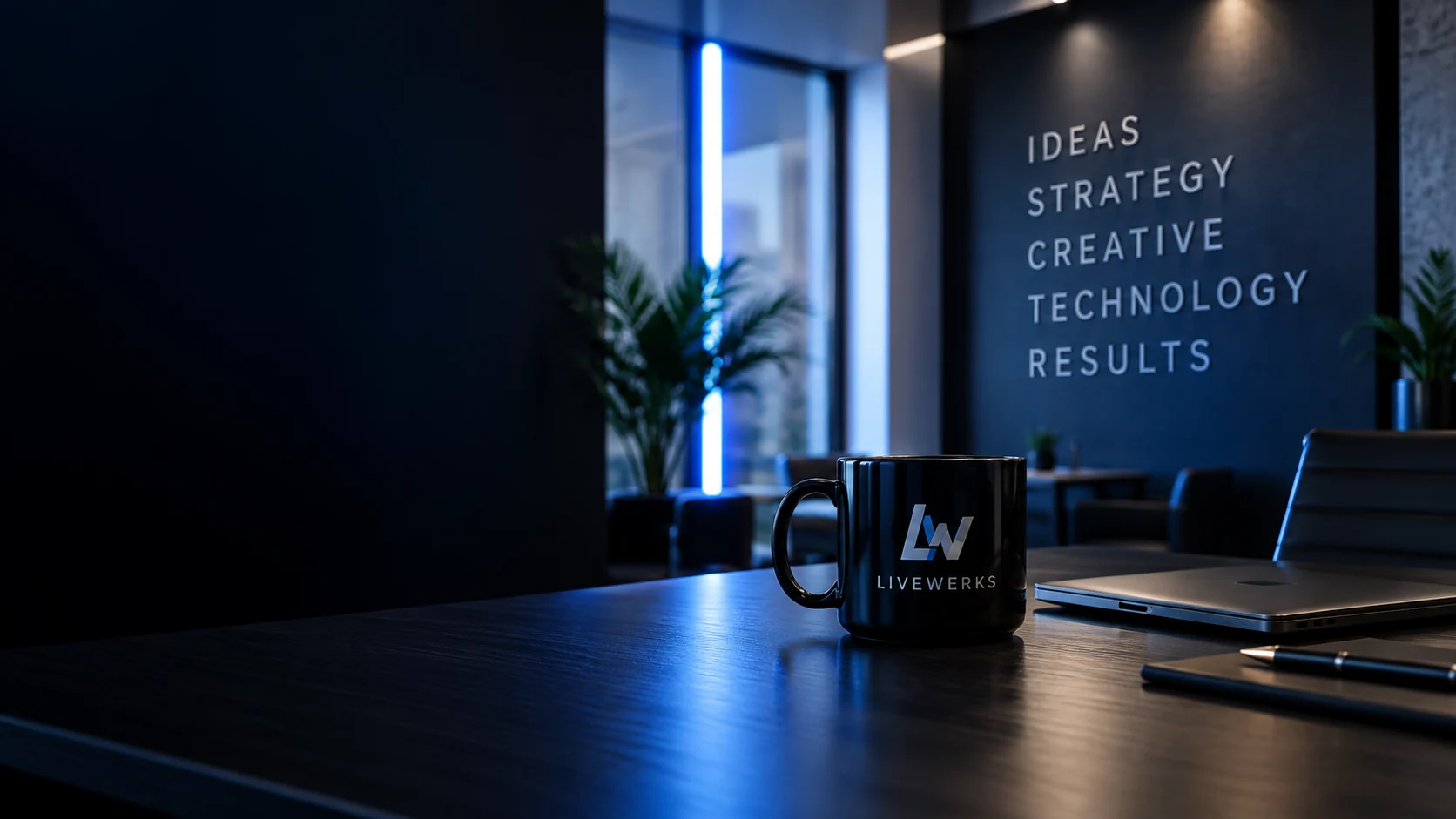 Conceptual Livewerks office scene with a branded mug, laptop, and blue lighting.