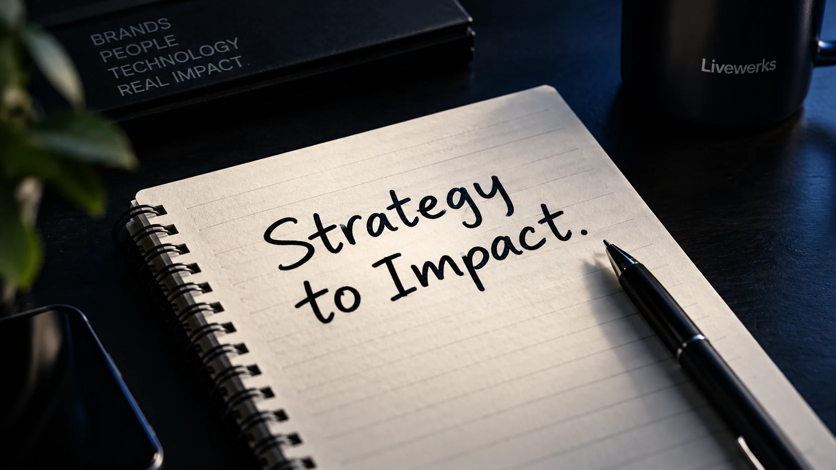 Strategy to Impact notebook and pen on a dark desk.